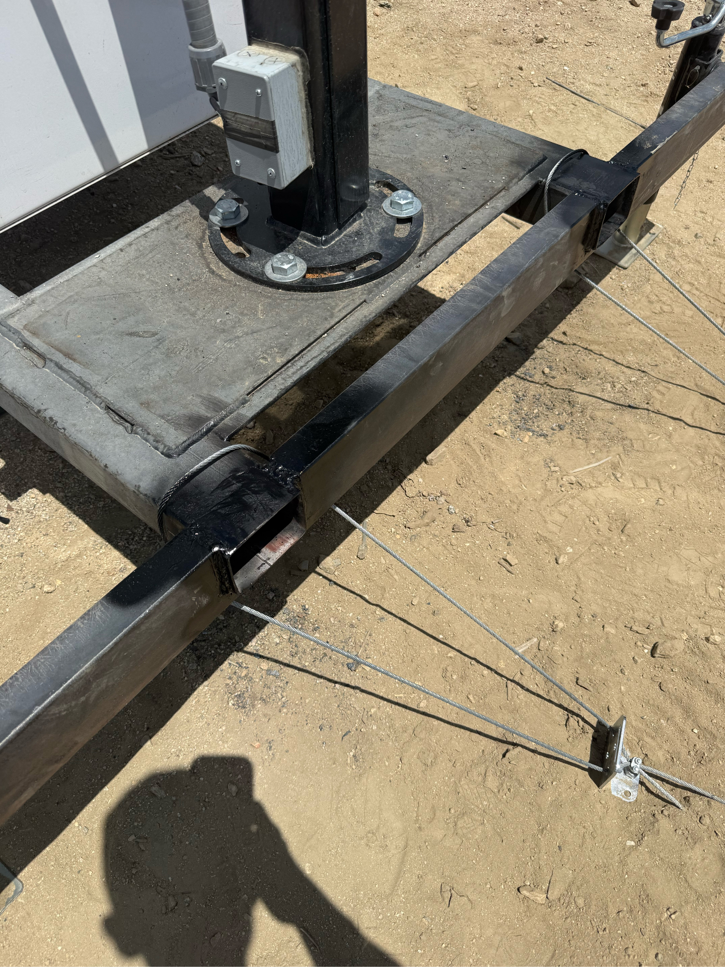 Fabricated post base with tension cable anchors